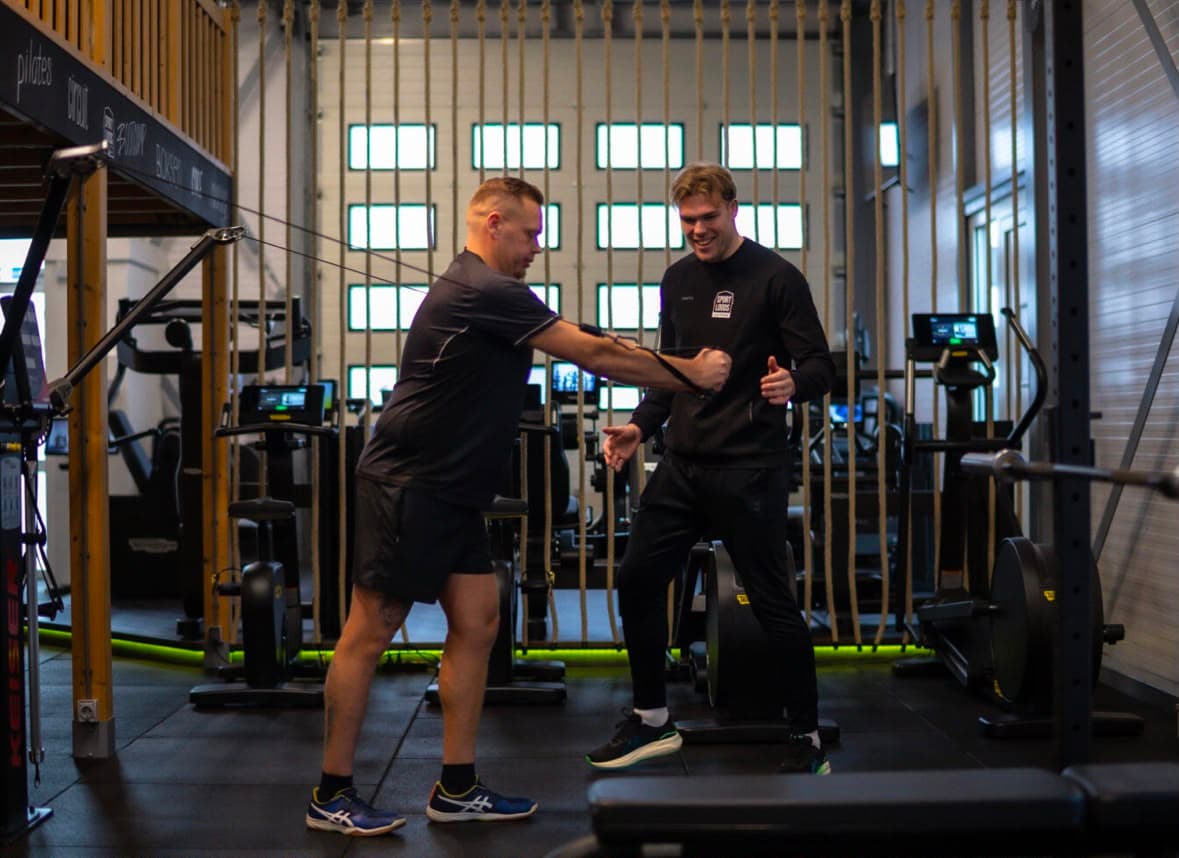 Julius coacht een klant op de kabelmachine in De Sportloods in Eefde, beide geconcentreerd